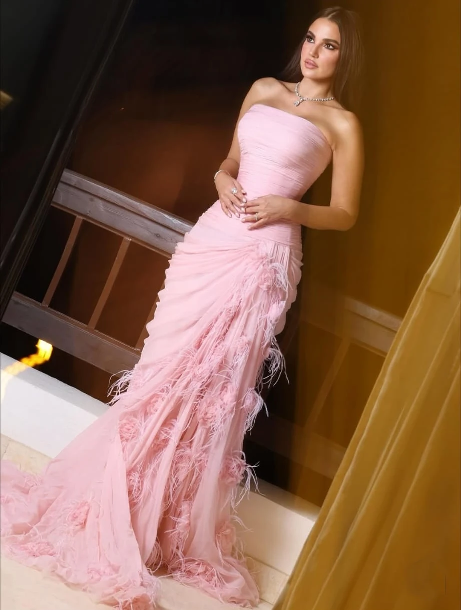 Hommage délicat à Octobre Rose à El Gouna : Dorra opte pour un rose ballerine, couleur-symbole de la sensibilisation au cancer du sein. La robe bustier drapée sculpte la taille, tandis que la jupe fluide, animée de plumes et fleurs ton sur ton, crée un mouvement cinématographique. Parures fines et mise en beauté lumineuse laissent parler la coupe. Un look poétique et solidaire : élégance maîtrisée, message clair, la féminité engagée qui capte la lumière sans la monopoliser. dora-zarouk-octobre-rose